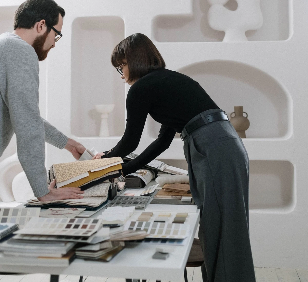 Two people comparing material swatches and product samples on a table